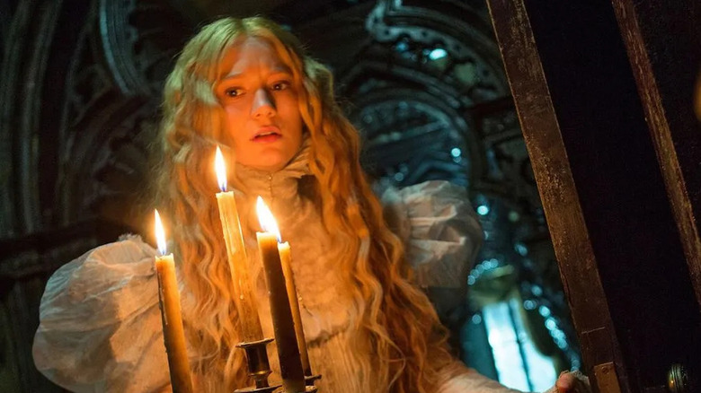 Edith holding a candelabra and looking scared in Crimson Peak