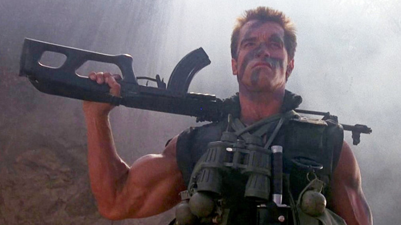 John holds a machine gun on his shoulder in Commando