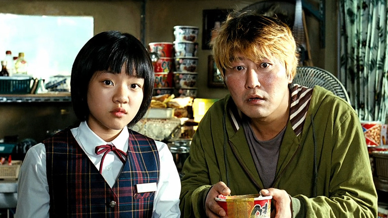 Park Gang-du and Hyun-seo watching the news with interest in The Host