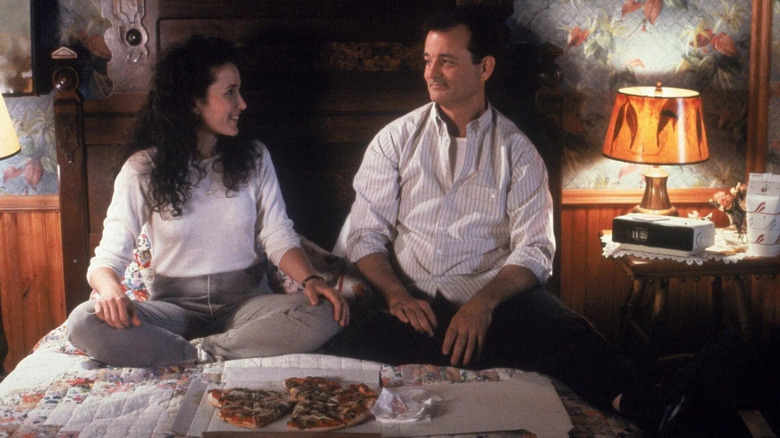 Phil and Rita smiling on bed while eating pizza in Groundhog Day (1993)