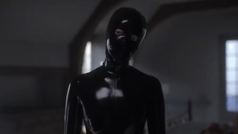A woman in black latex tilts her head ominously in American Horror Story