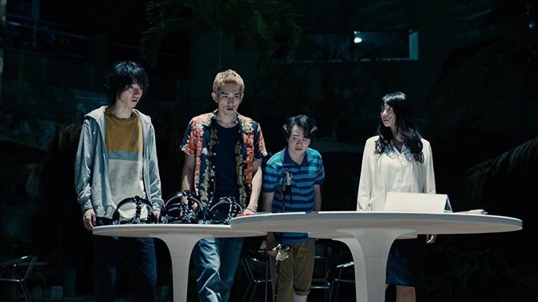 Shuntaro, Yuzuha, Ryohei, and Ginji stand around a table in Alice in Borderland.