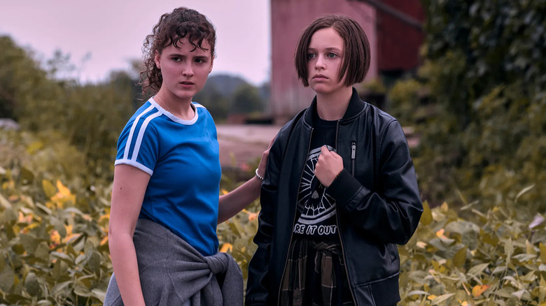 KJ and Mac stand outside behind the barn in Paper Girls.