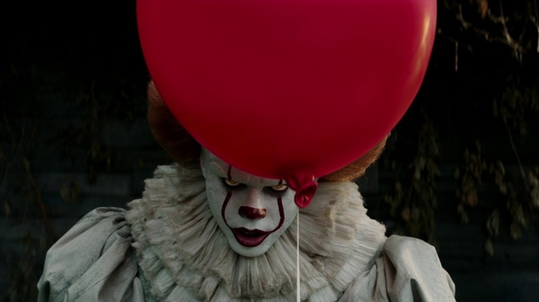 Pennywise the Clown menacingly holds a red balloon in "It" (2017)