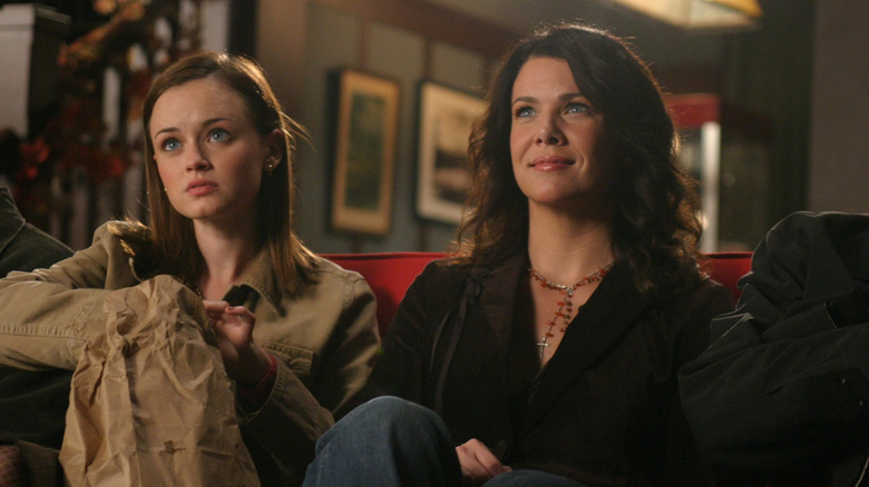 Rory Gilmore eating popcorn and watching a movie with Lorelei Gilmore on a red couch