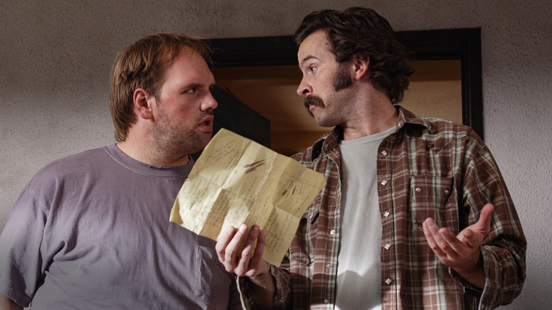 Earl shrugs while showing a piece of paper to Randy in My Name is Earl.