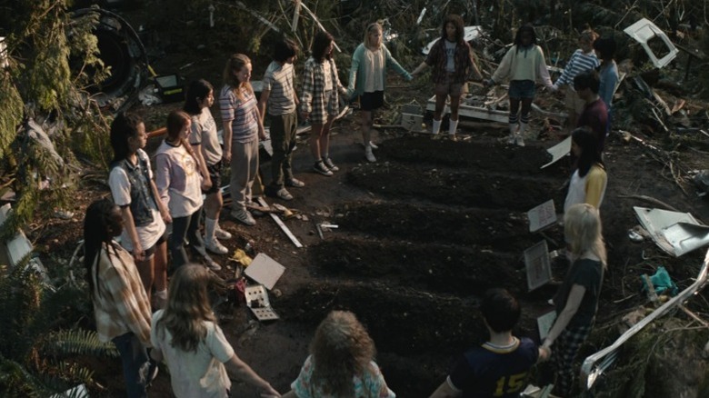 The survivors of the plane crash hold hands in a circle on "Yellowjackets" (2021-present)