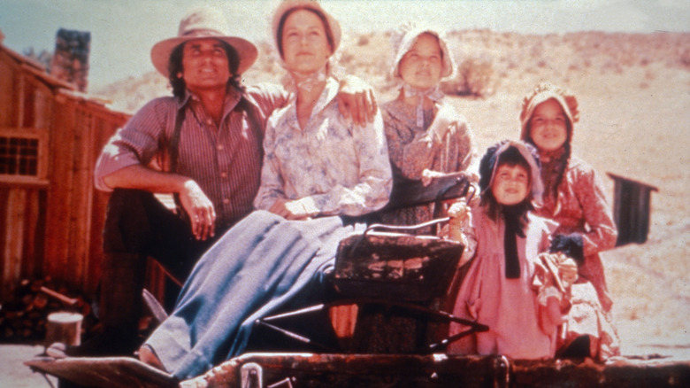The Ingalls family sits on the wagon and looks into the distance in Little House on the Prairie