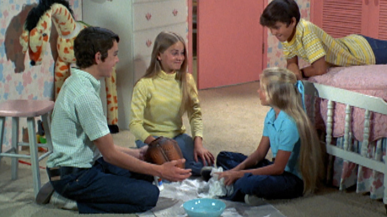 Greg, Marsha, Jan, and Peter sit in the bedroom making crafts in the Brady Bunch