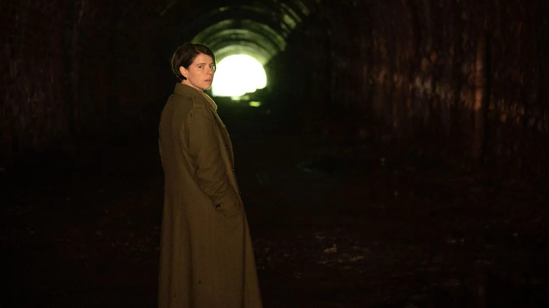 Harper looking alarmed walking through a tunnel in Men