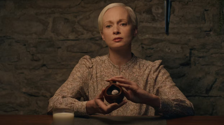 Darcy holding a glass eye in a container thoughtfully in Oddity