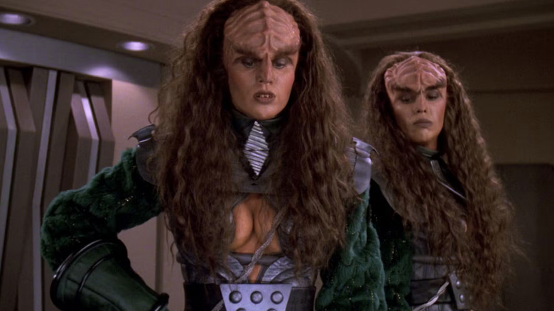 L'Ursa and B'Tor stand in the conference room looking at a knife on a table in Star Trek: The Next Generation