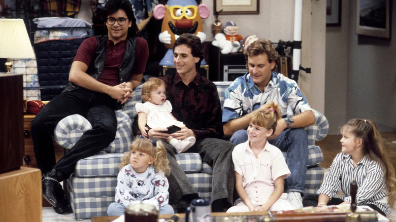 The cast of "Full House" sitting on a patterned couch.