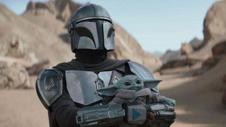 Din Djarin holding Grogu in The Mandalorian