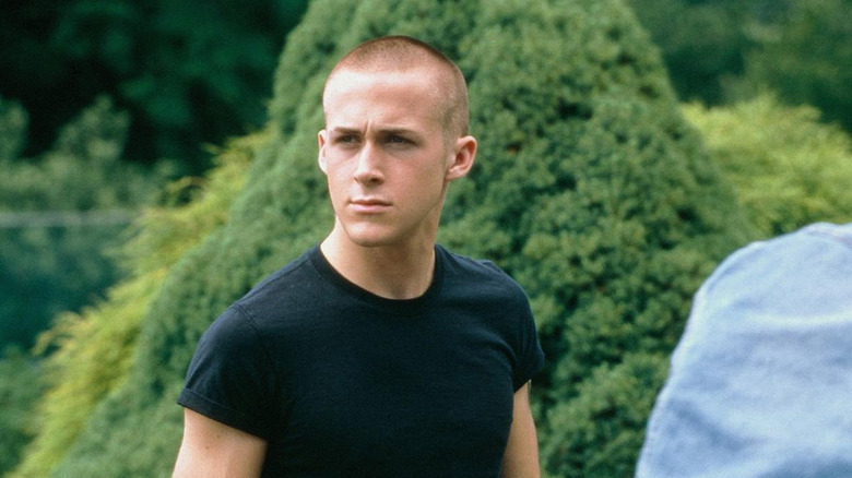 Danny with a shaved head standing near greenery
