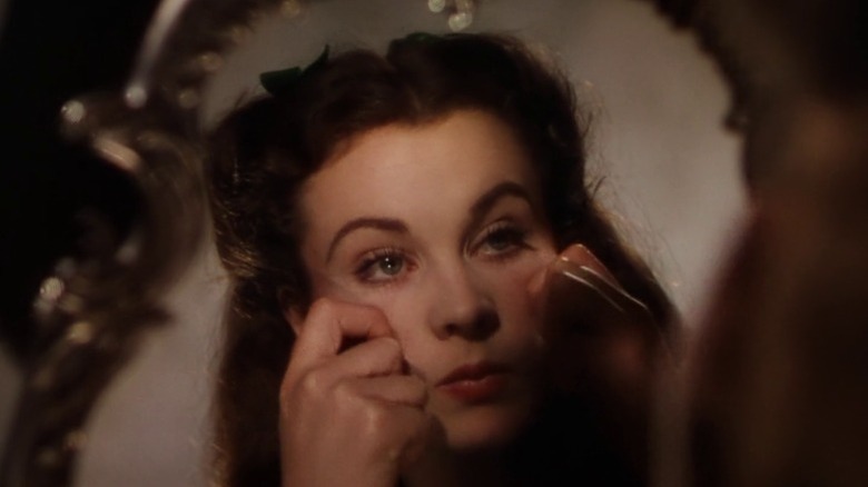 Scarlett O'Hara applying makeup while looking in the mirror in Gone with the Wind