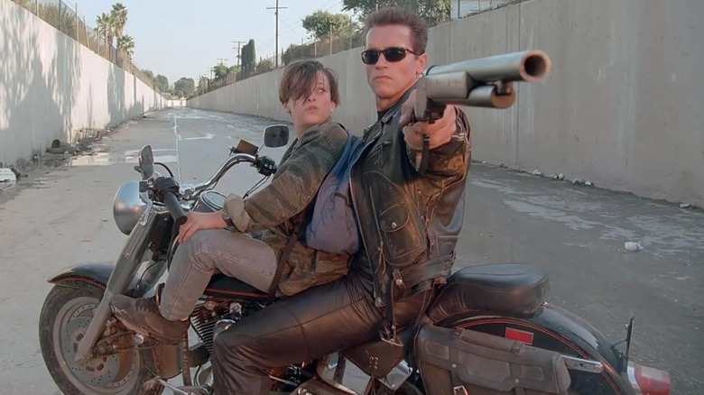 The T-800 aiming a shotgun with John Conner on his motercycle in Terminator 2: Judgment Day