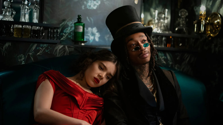 Emily Dickinson wears a red dress while resting her shoulder on Death, in a black suit and top hat, in "Dickinson"