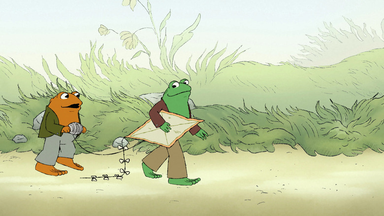 Green Frog holds a kite as brown Toad follows behind him holding the string as they walk through the woods in "Frog and Toad"