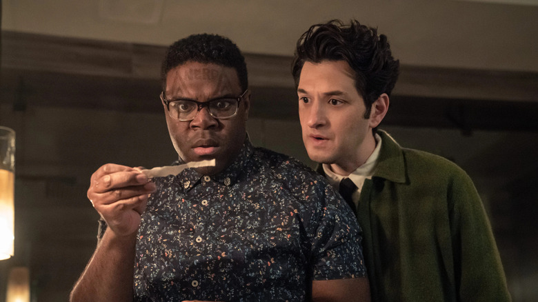 Aniq looking at a strip of paper while Yasper Lennov looks over his shoulder in "The Afterparty"