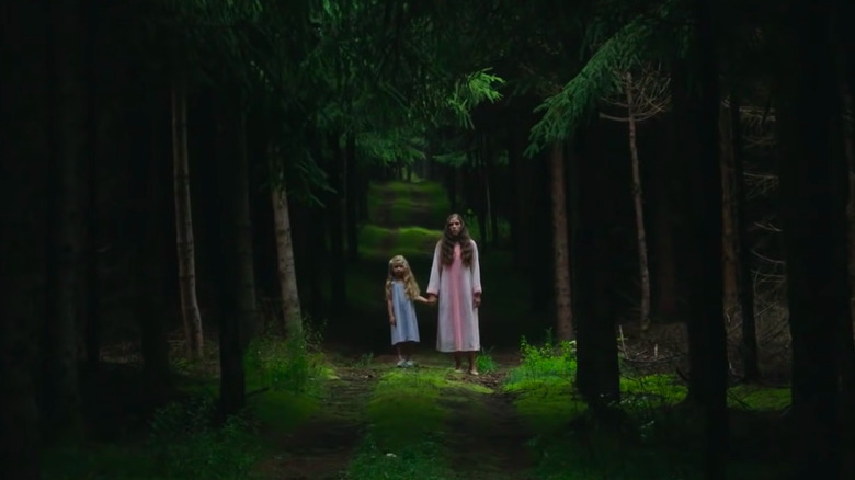 A woman and child in the woods staring ahead