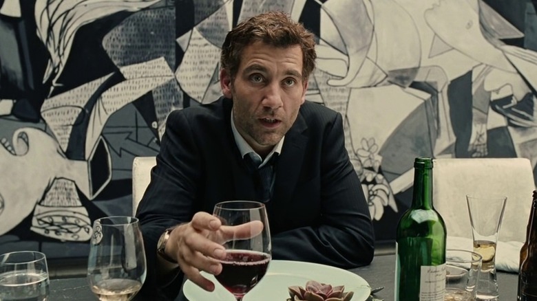 Theo clutches a glass of wine while sitting in front of Picasso's Guernica in "Children of Men"