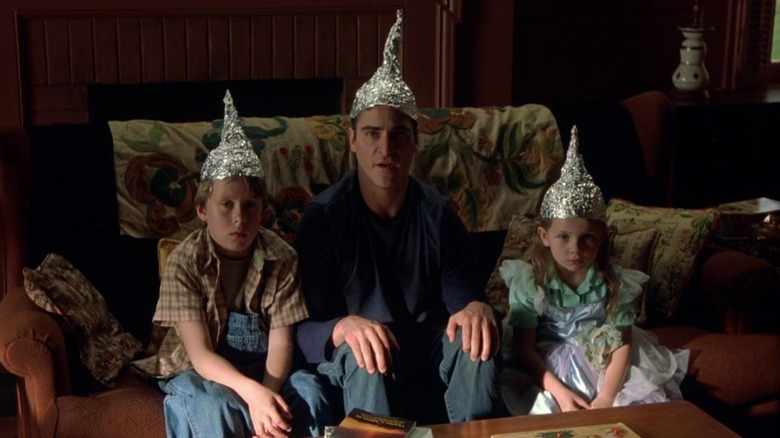 Morgan, Merrill, and Bo sitting on the couch in tin foil hats in "Signs"