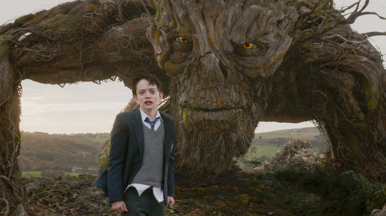 Conor with a scared face as the monster stands behind him in "A Monster Calls."