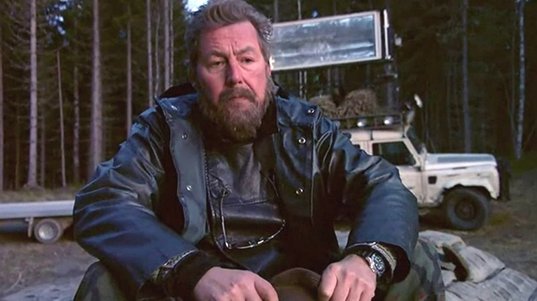 Hans sitting on a rock outside in "Trollhunter."