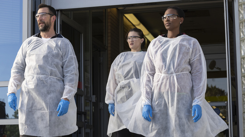 Drs. Robby, Santos, and Collins wear protective equipment while waiting for an ambulance in The Pitt