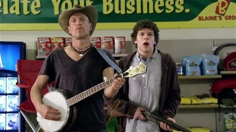 Woody Harrelson holding a banjo next to Jesse Eisenberg