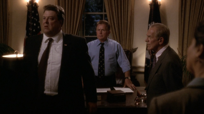 Bartlet standing behind his desk with Goodman and Leo in front