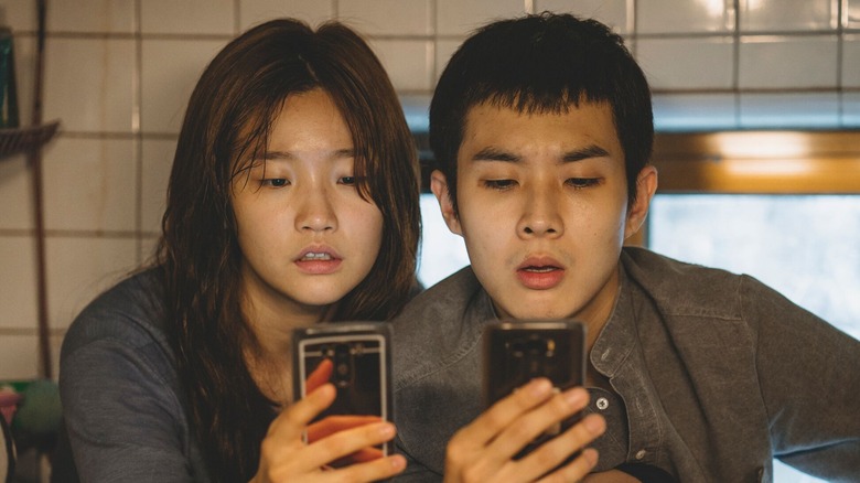 Ki-Jung and Ki-Woo searching for reception in the bathroom