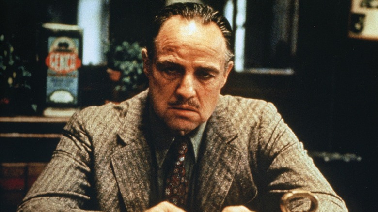 Older Don Vito Corleone looking irritated at his desk