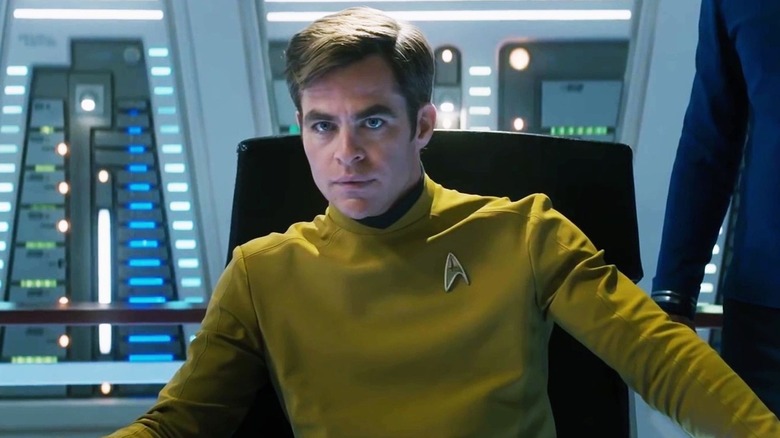 Captain Kirk wears a yellow Starfleet uniform while seated in a captains chair in 