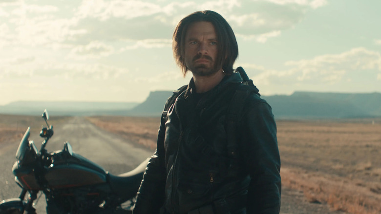 Bucky Barnes stands on a road in the middle of the desert in a black jacket in front of a motorcycle in "Thunderbolts"