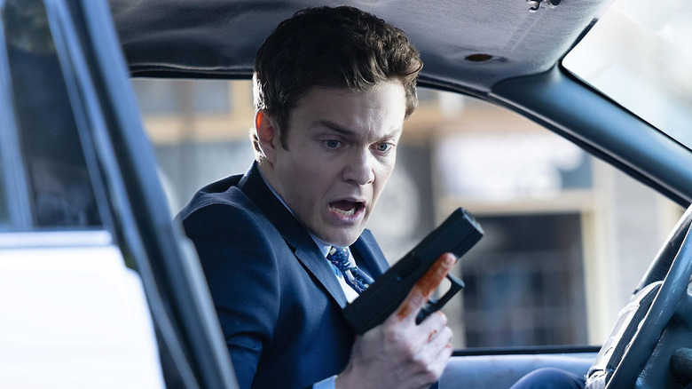 Nathan looking at his hand holding a gun in "Novocaine" (2025)