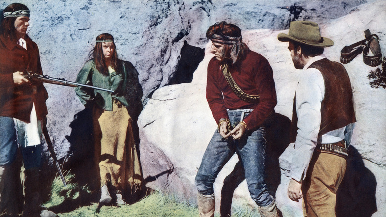 Hondo, Nalinle, and Al Sieber surrounding a chained Massai in "Apache" (1954)