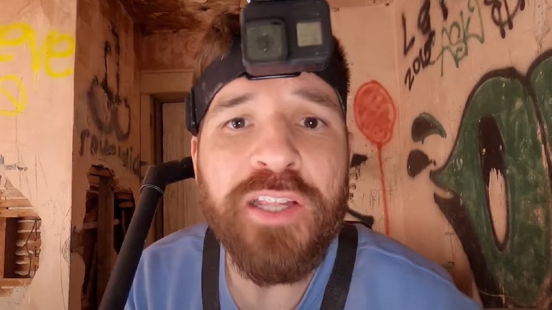 Shawn standing in front of a graffitied wall in "Deadstream."