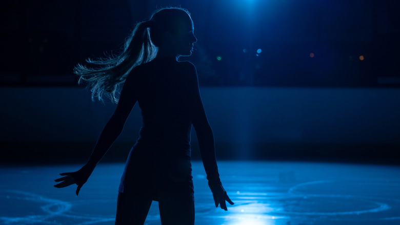 Silhouette of a young woman ice skating in the dark