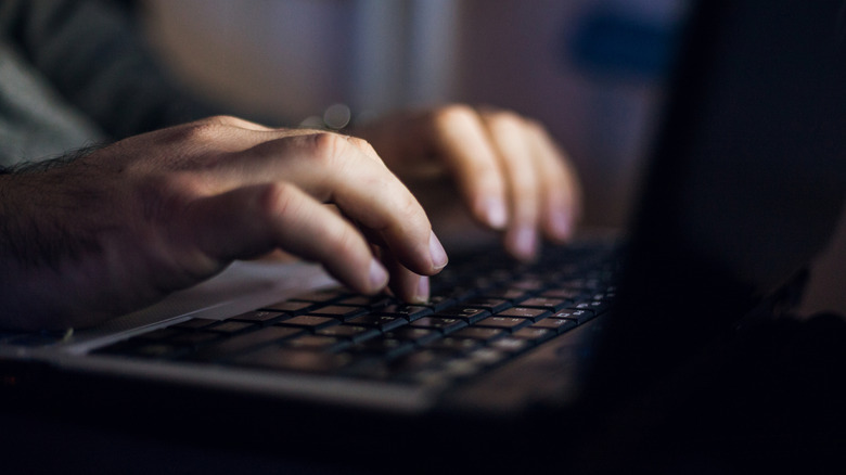 A man typing on a laptop at night