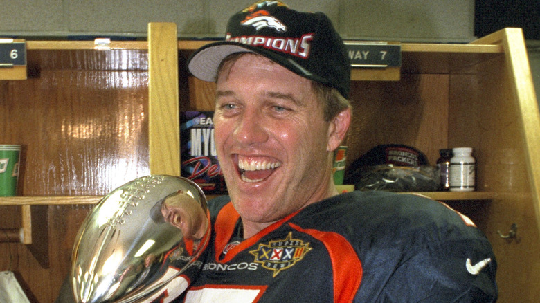 John Elway smiling and holding the Vince Lombardi trophy