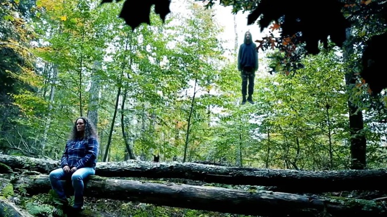 Ivy sits on a fallen tree in a forest while Echo's spirit hovers in the air near her in 