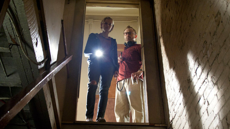 Claire and Luke peer down the stairs into the basement in The Innkeepers