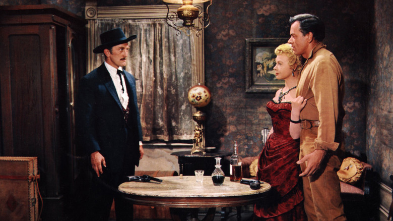 Doc Holliday, Kate Fisher, and Johnny Ringo standing around a table in Gunfight at the O.K. Corral
