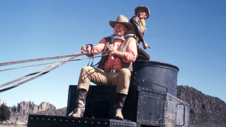 Taw and Lomax riding an armored wagon in The War Wagon