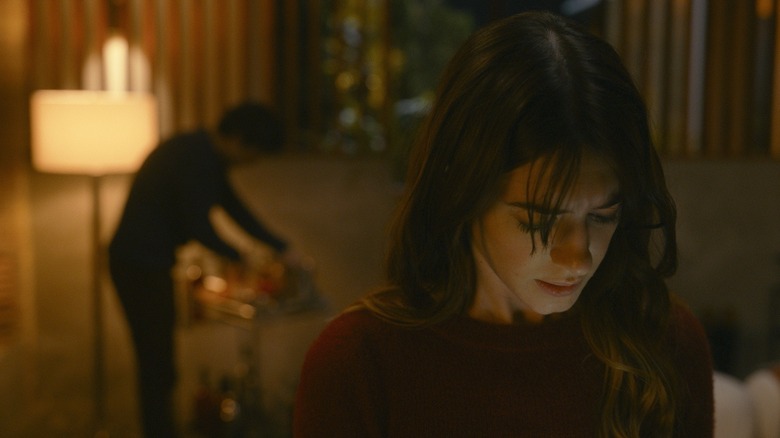 Noa looking at her phone with Steve behind her in Fresh