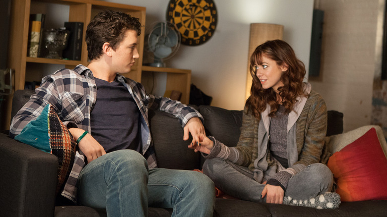 Alex and Megan sitting on the couch holding hands in Two Night Stand
