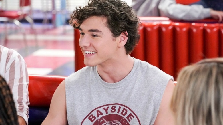 Jamie in a Bayside Tigers muscle shirt sitting in a restaurant booth in Saved by the Bell (2020)