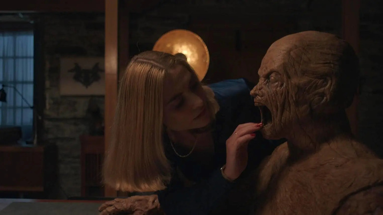 Yana investigating a wooden figure's mouth in Oddity